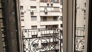 A balcony with a metal railing and a view of a multi-story building with balconies.