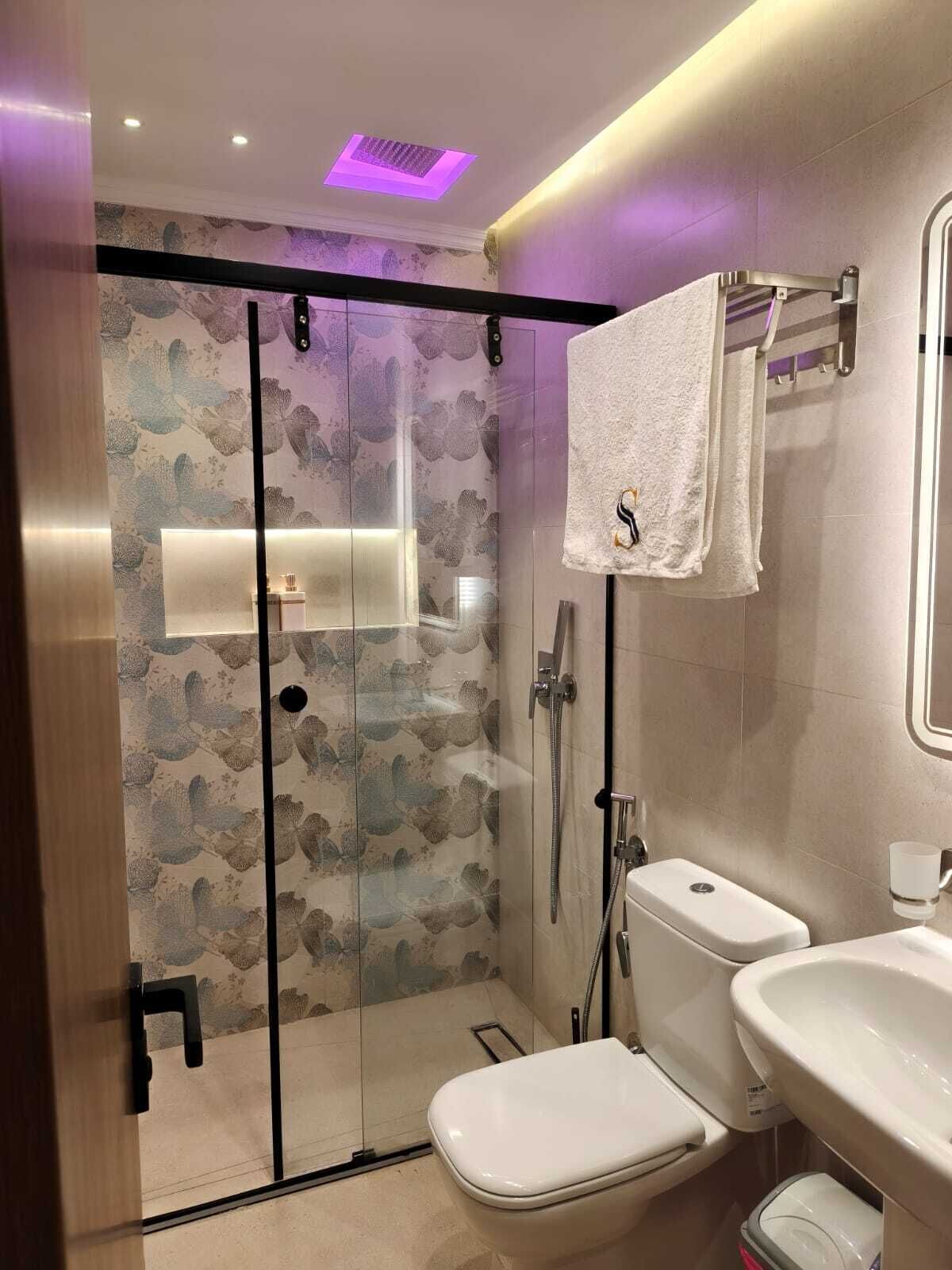 A modern bathroom with a glass-enclosed shower, a toilet, and a sink.