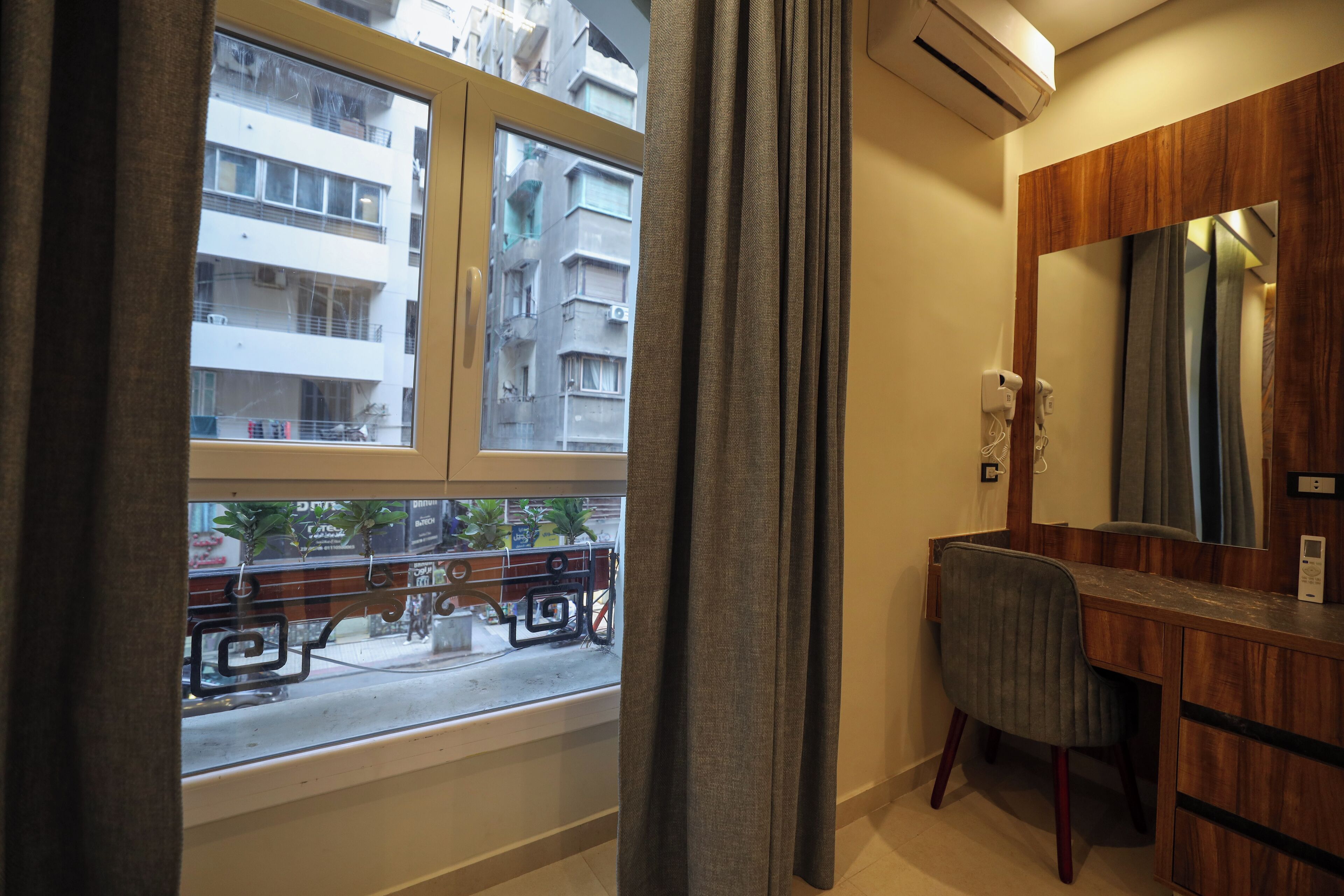 A room with a window, a wooden vanity with a mirror, and a chair.