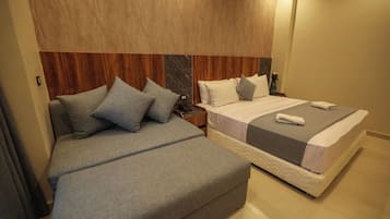Ein Hotelzimmer mit zwei Betten, einem hölzernen Kopfteil und einem Nachttisch mit Lampe.