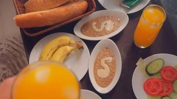 A breakfast tray with bread, bananas, soup, eggs, and a glass of orange juice.