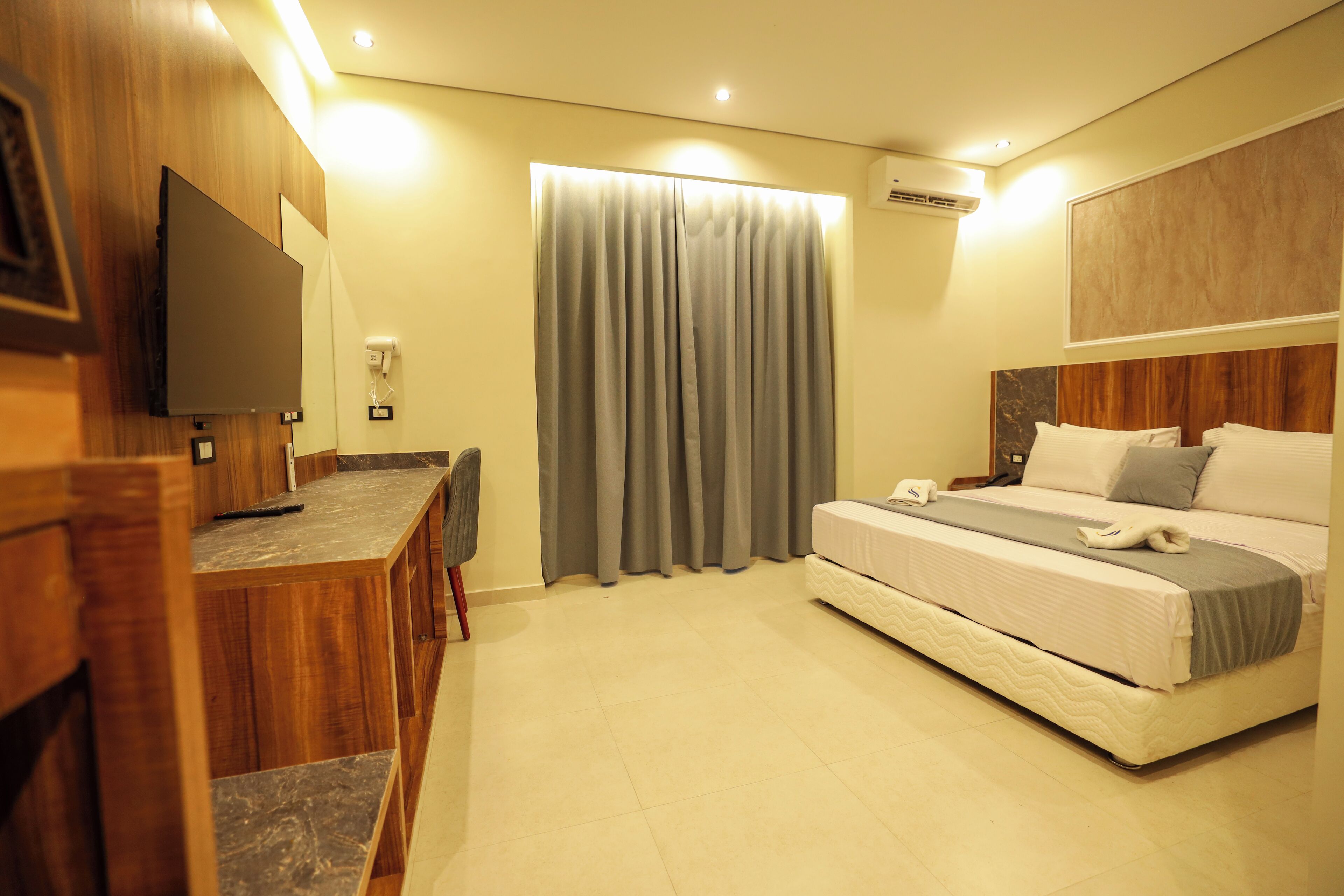 Una habitación de hotel con cama, escritorio, silla y televisión.