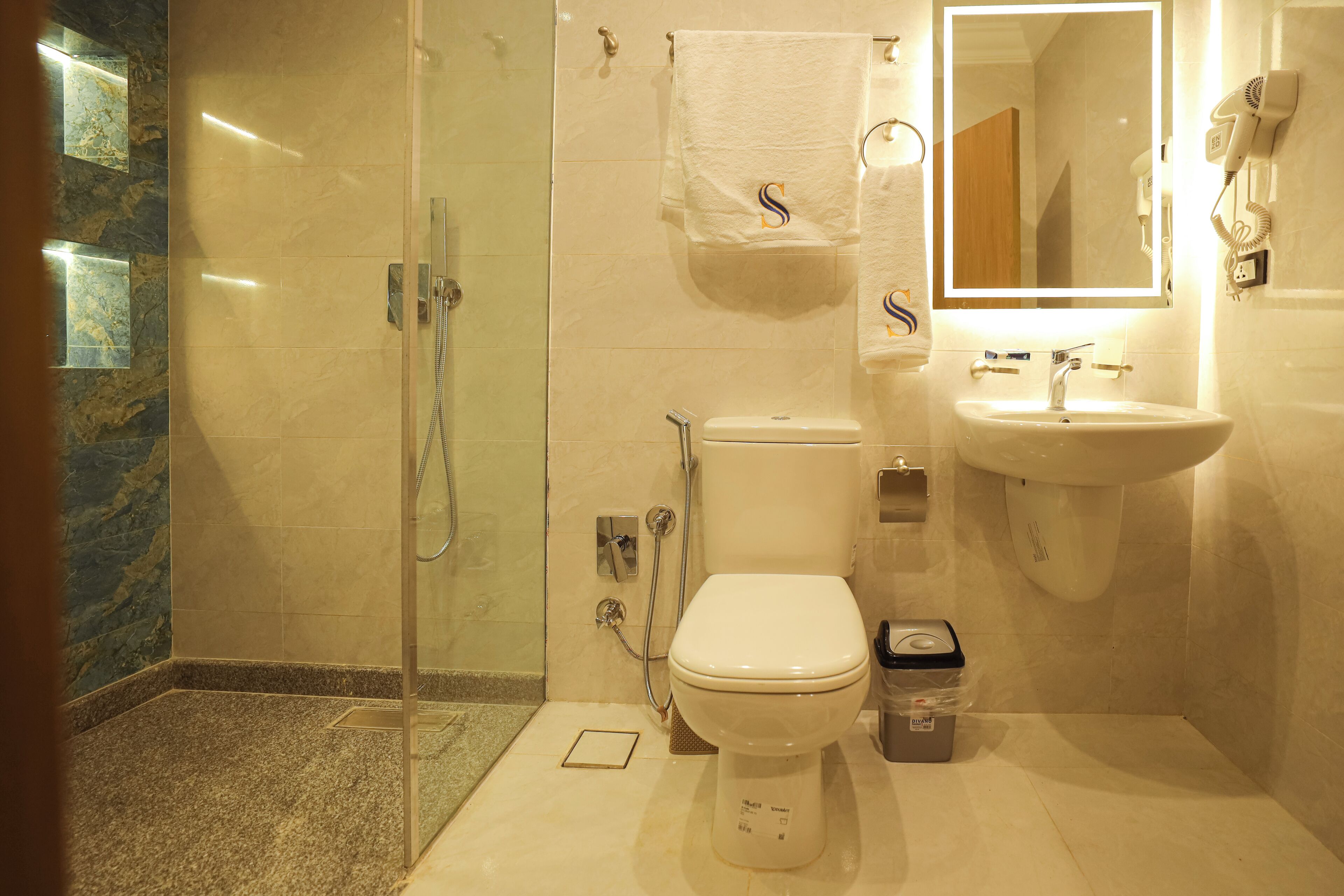 Un baño con ducha envuelta en vidrio, inodoro, lavamanos y espejo.