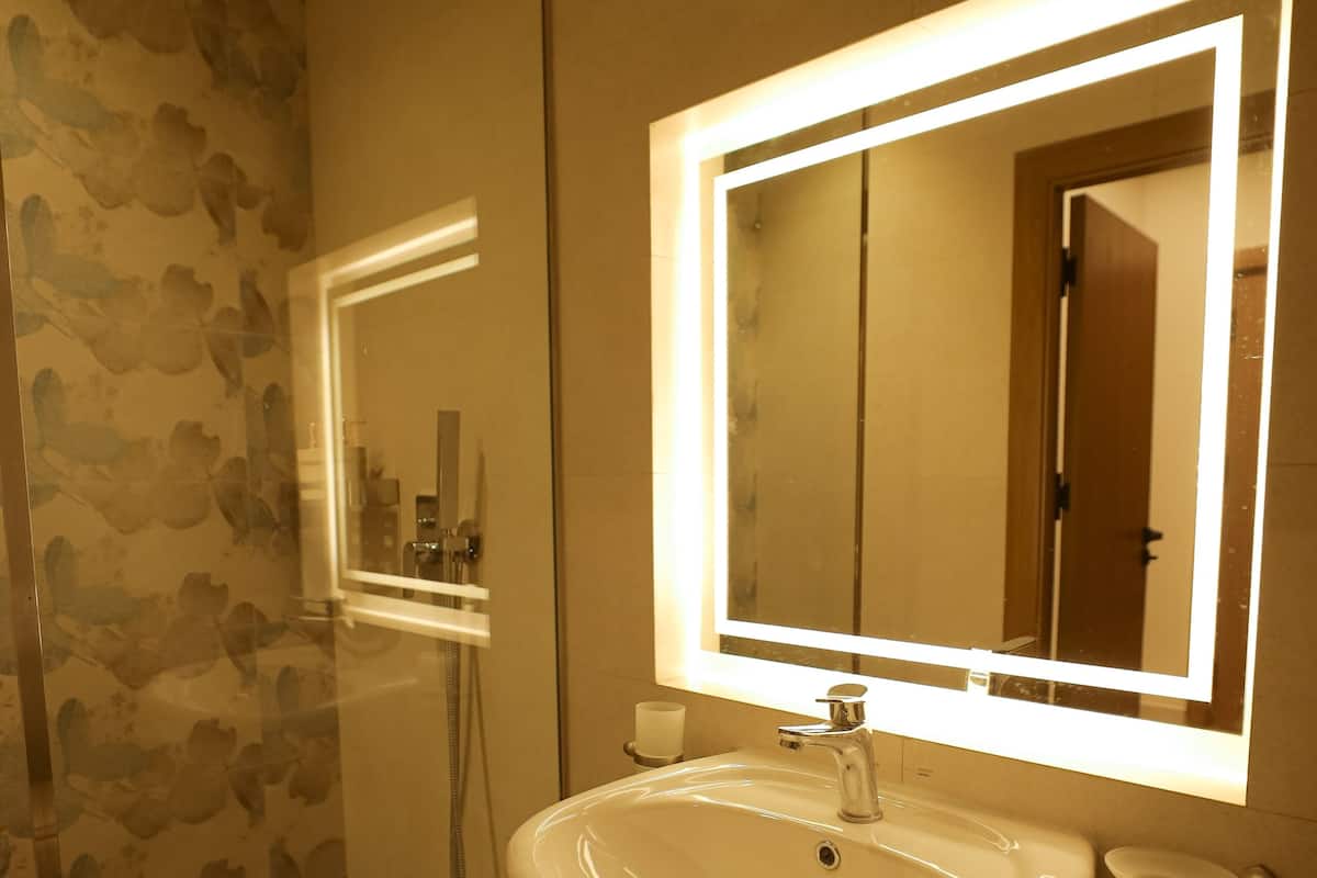 Baño con lavamanos, espejo y ducha.