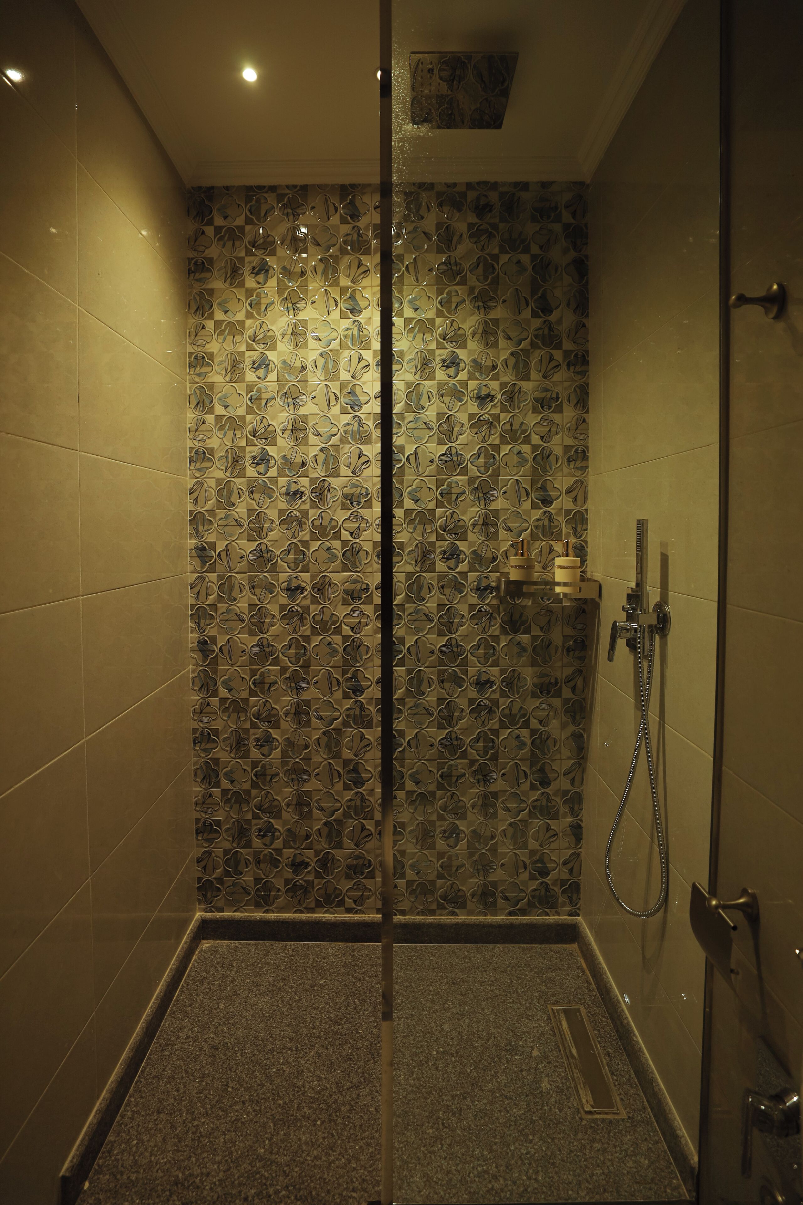 Ducha con mampara de vidrio, paredes alicatadas y ducha.