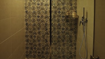 Ducha con mampara de vidrio, paredes alicatadas y ducha.