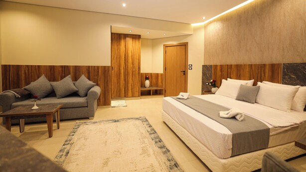 A modern hotel room with a bed, sofa, and a small table.