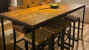 Ein Essbereich mit einem Holztisch, Bänken, einem Schrank mit Glastüren und hängenden Pendelleuchten.