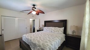 Ein Schlafzimmer mit einem Bett, Nachttischen, einem Deckenventilator und einem Kleiderschrank.