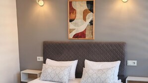 Ein modernes Schlafzimmer mit einem großen Bett, zwei Nachttischen, einer Hängelampe und einer Wandleuchte.
