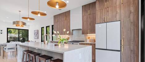 Cocina moderna con una isla central, armarios de madera e iluminación colgante.