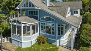 A two-story house with a large front porch, a covered patio, and a chimney. - Lake Shore Living - lakefront, pool, sleeps 16 (New Buffalo)