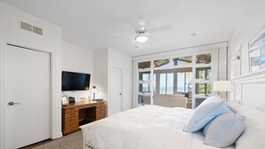 A bedroom with a bed, a desk, a television, and a view of the outdoors. - Lake Shore Living - lakefront, pool, sleeps 16 (New Buffalo)