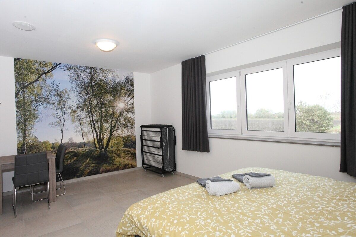 A hotel room with a bed, a desk, a chair, and a large window.
