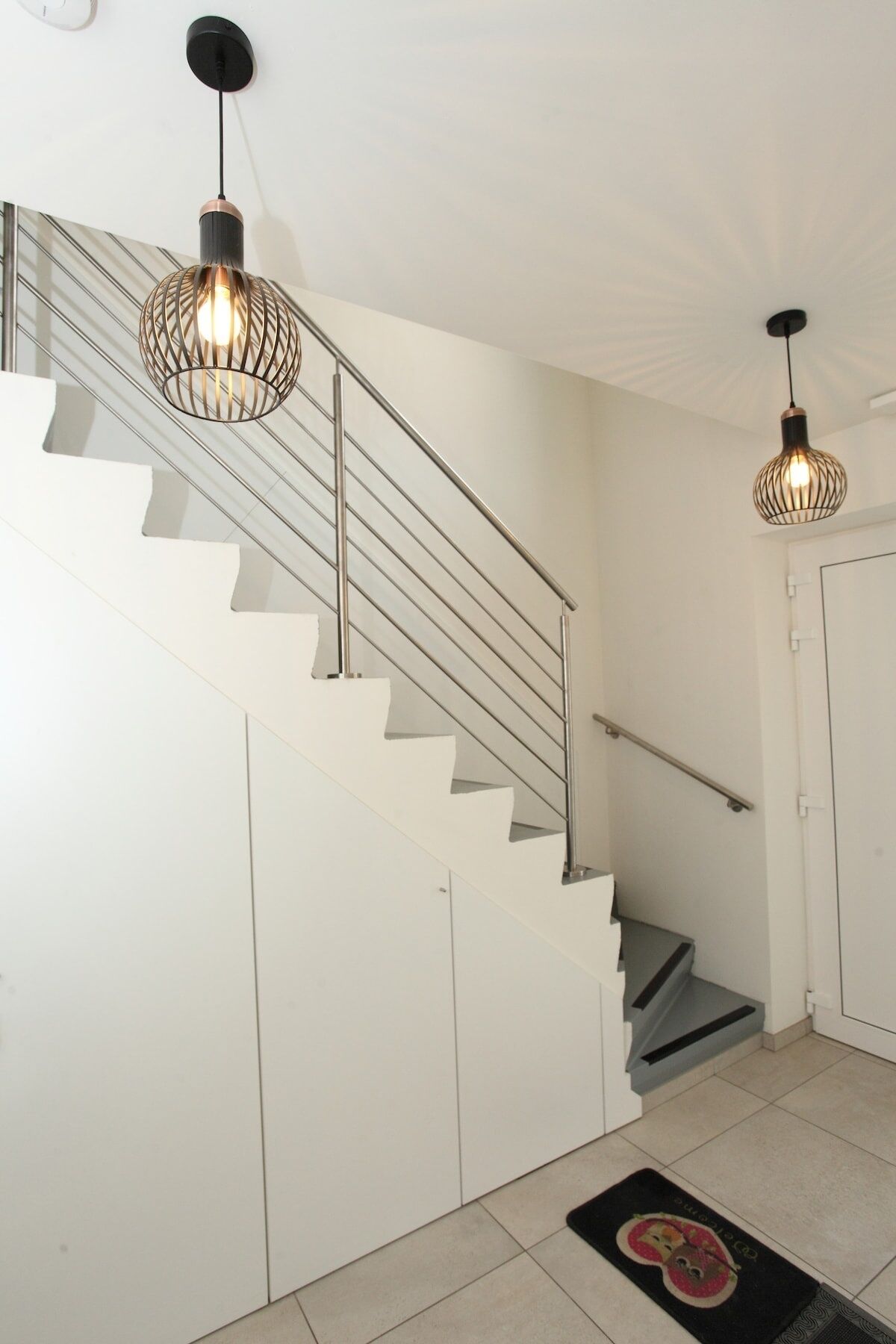A staircase with metal railings and two pendant lights with exposed bulbs.