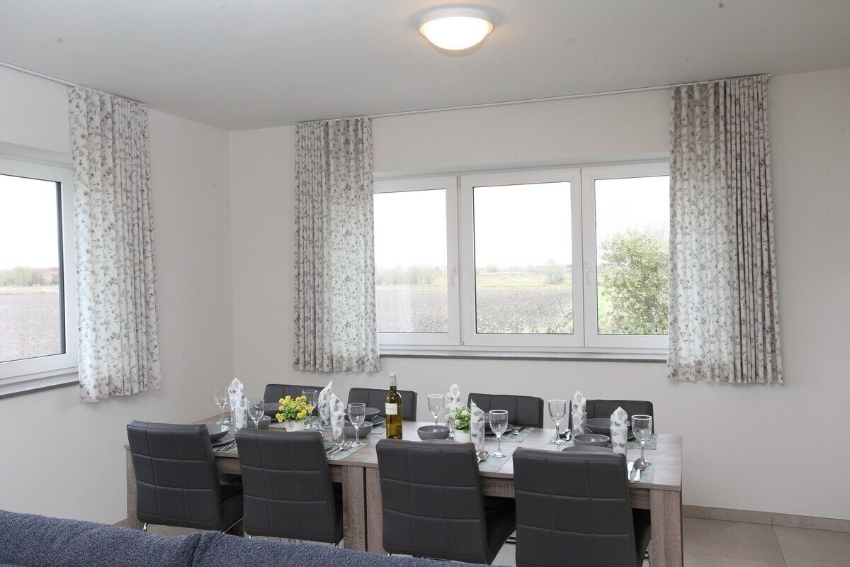 Comedor con una mesa preparada para cuatro personas, cortinas y ventana con vistas.
