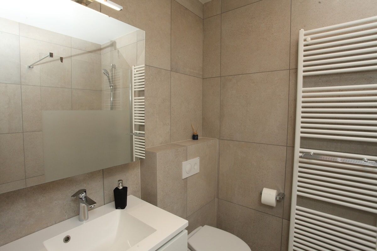 A modern bathroom with a white sink, mirror, and toilet.