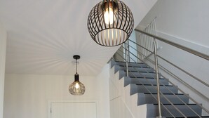 A modern interior with a staircase, a door, and two pendant lights.