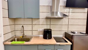 Een moderne keuken met grijze kastjes, een roestvrijstalen spoelbak, een koffiezetapparaat en een geïntegreerde inductiekookplaat.