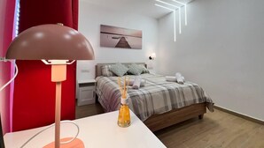 Een moderne slaapkamer met een bed, nachtkastjes, een lamp en een aan de muur hangend schilderij.