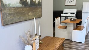 Un meuble en bois avec des tiroirs, un tableau représentant un paysage encadré, un chandelier et un panneau posé sur une table.