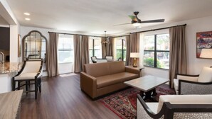 A spacious living room with a sofa, chairs, a coffee table, and a dining area.