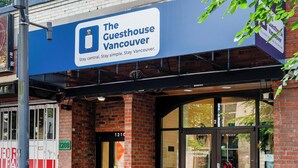 Un edificio de ladrillo con un cartel que dice 'The Guesthouse Vancouver' en la entrada.