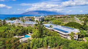 A resort with multiple buildings, a swimming pool, and a view of the ocean and a mountain. - Oceanview Retreat Walk to Beach & Restaurants (Kihei)