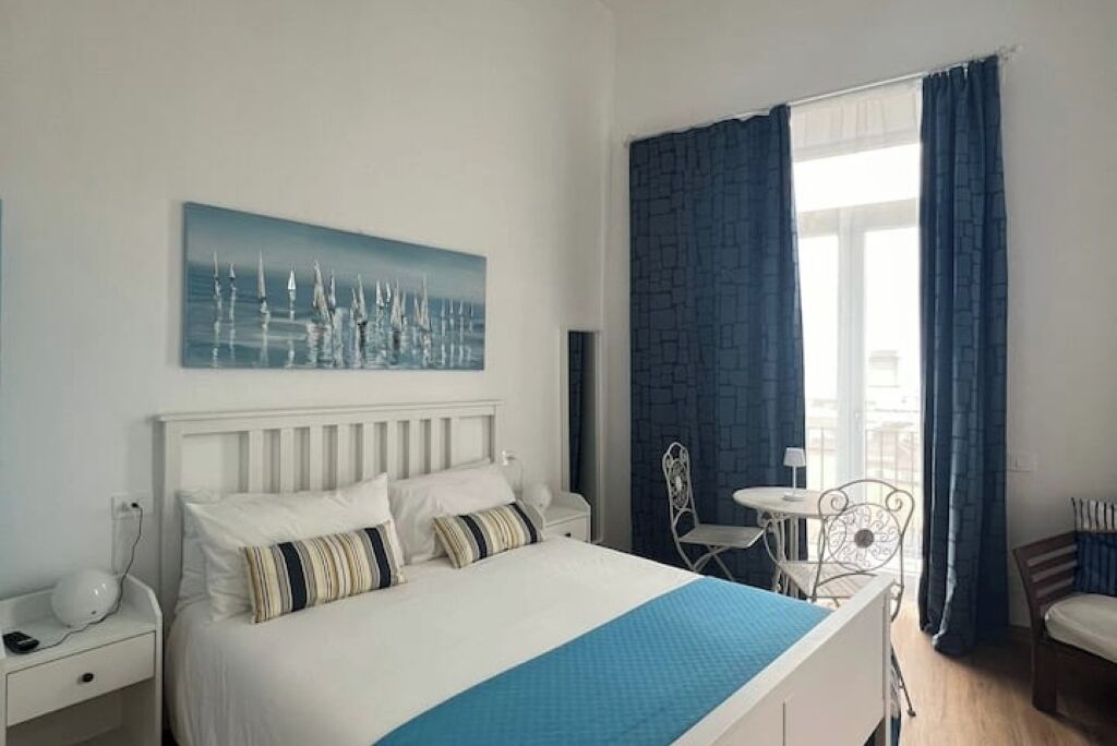 Een keurig opgemaakt hotelkamer met een bed, een tafeltje en stoelen.
