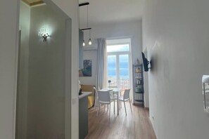 A modern kitchen with white cabinets, a dining area with a table and chairs, and a large window with a view of the sea. - Breathtaking views of the sea and the ancient city (Salerno)