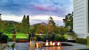 A patio with a fire feature, outdoor seating, and a view of a landscaped garden. - Lux Napa Escape | King Bed + Steps to Wineries (Napa)