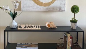 Een kamer met een zwarte console tafel waarop een 'I ♥ Maui' bord staat, een kleine potplant en een decoratieve schelp.
