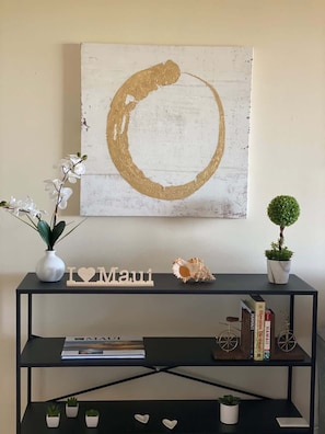 Ein Zimmer mit einem schwarzen Konsolentisch, der ein 'I ♥ Maui'-Schild, einen kleinen Blumentopf und eine dekorative Muschel zeigt.