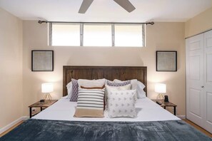 Ein Schlafzimmer mit einem großen Bett, zwei Nachttischen mit Lampen, einem Holzkopfende und zwei gerahmten Bildern an den Wänden.