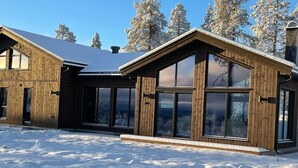 A wooden cabin with large windows and a snow-covered landscape.