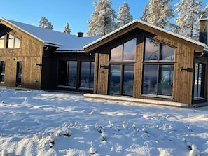 A wooden cabin with large windows and a snow-covered landscape.