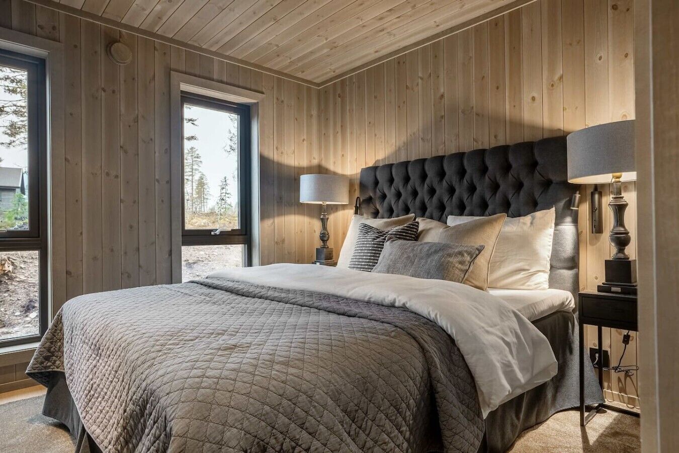 A bedroom with a large bed, wooden walls, and a window.