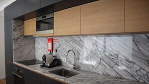 Een moderne keuken met een marmeren aanrechtblad, een inbouwoven en een koffieapparaat.