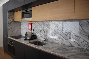 A modern kitchen with a marble countertop, a built-in oven, and a coffee machine. - 1-bedroom apartment with terrace (Porto)