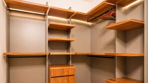 Un armario vestidor con varias repisas de madera y un módulo central con cajones.