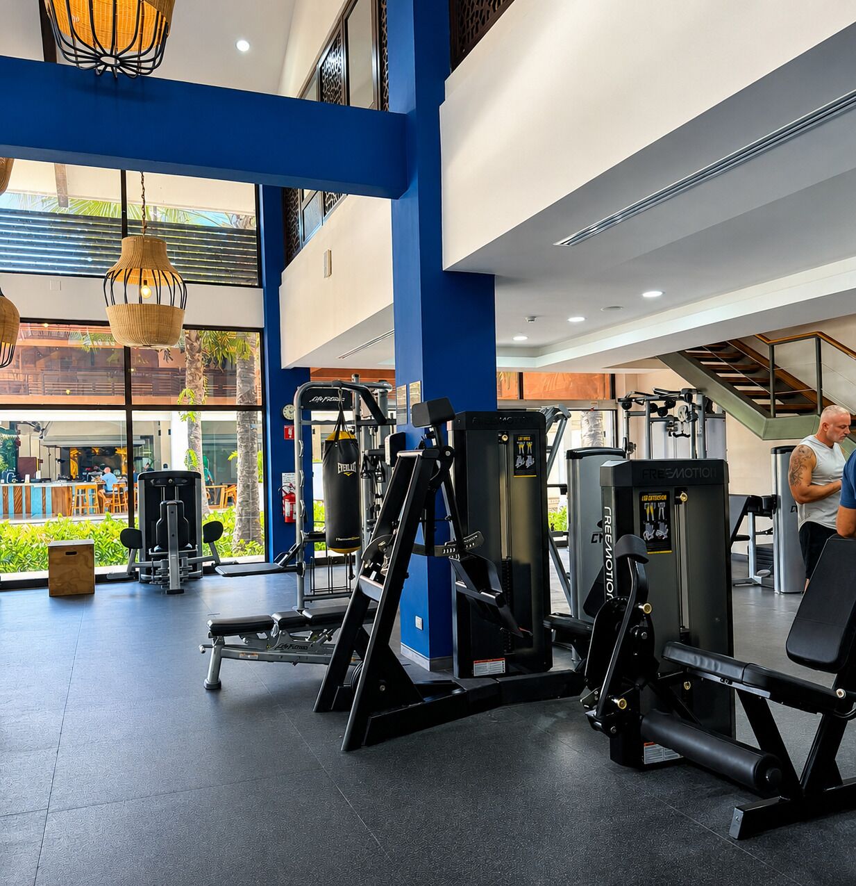 A gym with exercise equipment, large windows, and a view of the outside.