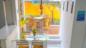 A compact living space with a dining area, a sofa, a bed, and a view of a colorful outdoor scene. - Apartment with gourmet balcony, 150m from Enseada beach. (Guarujá)