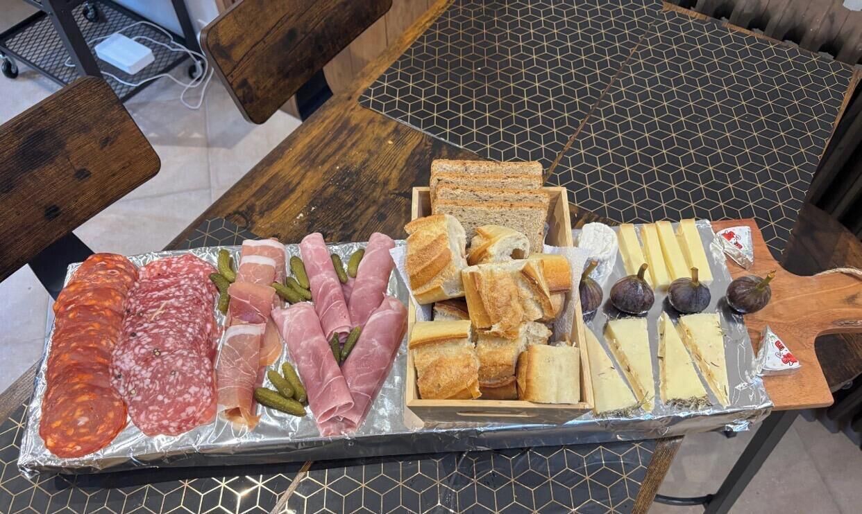A food platter with various meats, cheeses, and bread on a table.