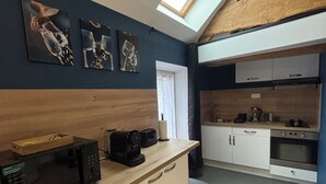 A modern kitchen with a skylight, a microwave, a coffee maker, and a trash bin. - Le Merisier (Épieds)