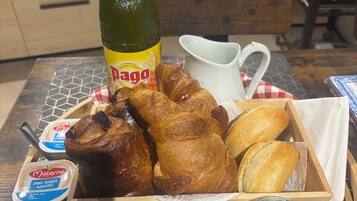 Uma bandeja de café da manhã com croissants, uma garrafa de Dango, um jarro, uma tigela de manteiga e um pote de geleia.