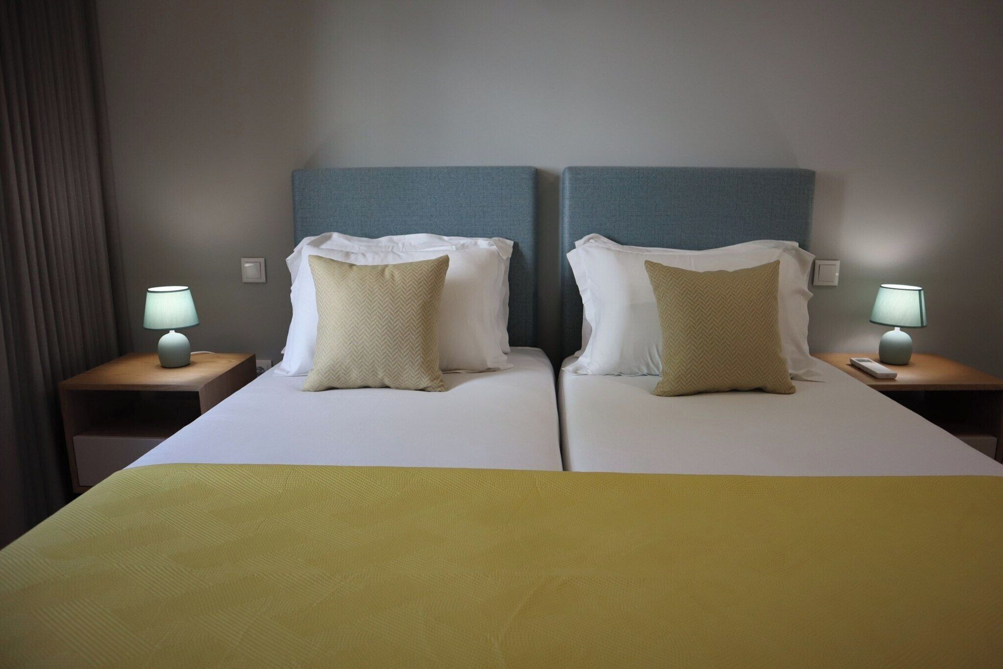 Un lit double avec deux tables de chevet, chacune équipée d’une lampe et d’une télécommande.