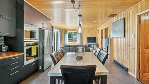 Une cuisine moderne avec un coin repas, un plafond en bois et un téléviseur fixé au mur.