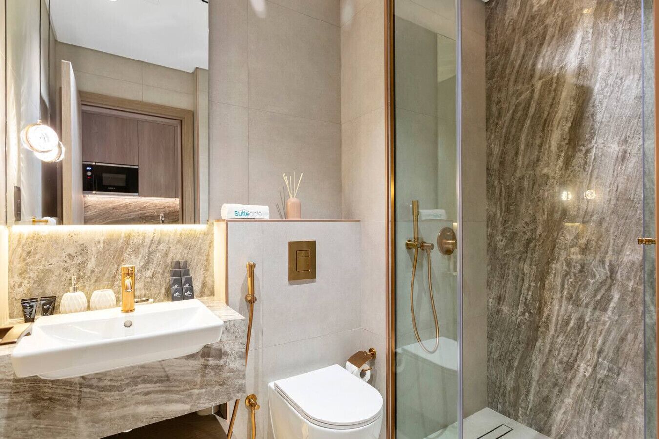 Un baño moderno con lavamanos de mármol, inodoro y ducha con mampara de vidrio.