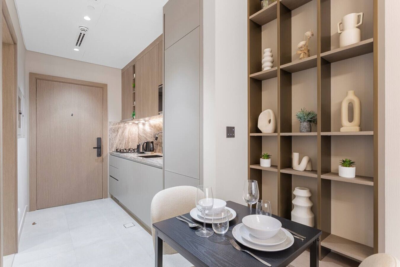 Una cocina moderna con una isla integrada, armarios de madera y un comedor con una mesa dispuesta para dos.