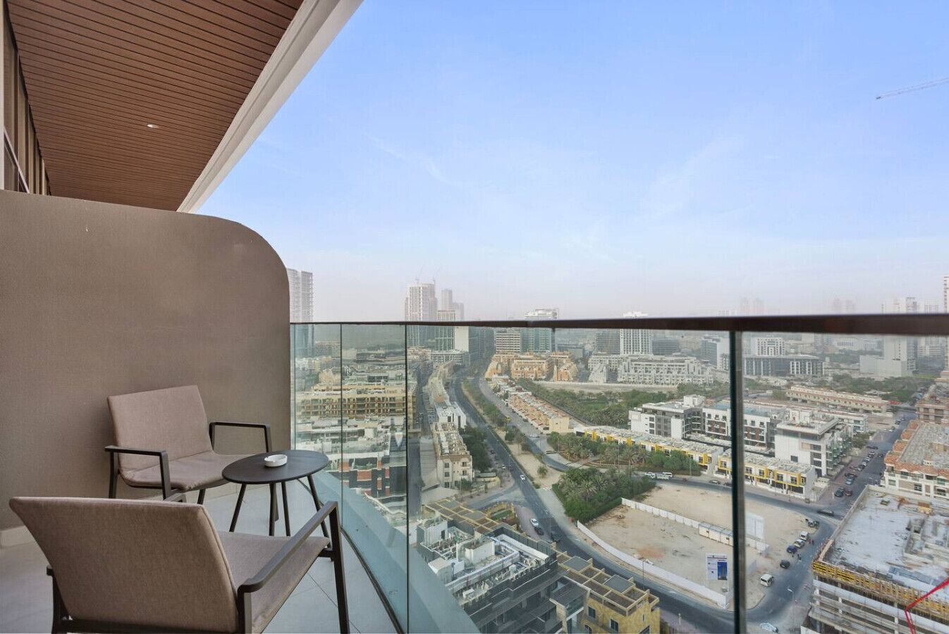 A balcony with a city view, two chairs, and a glass partition.